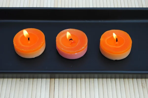 Оранжевые свечи в черной тарелке на бамбуке — стоковое фото