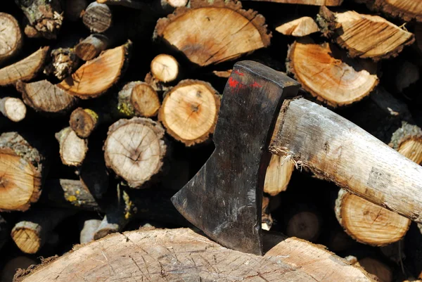 Eisenaxt im Holzstamm mit Holzstämmen auf Hintergrund — Stockfoto