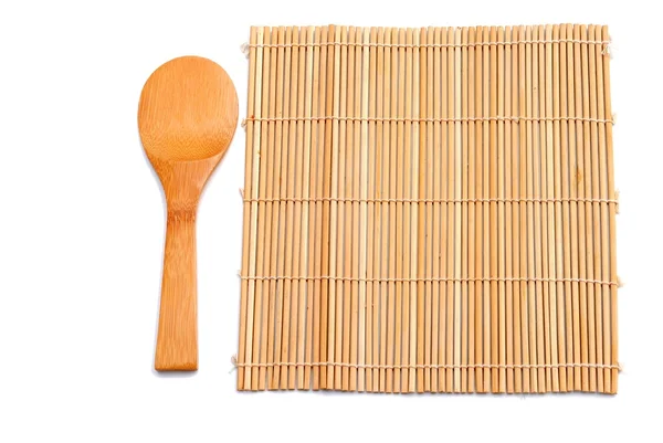 Wooden spoon beside bamboo placemat — Stock Photo, Image