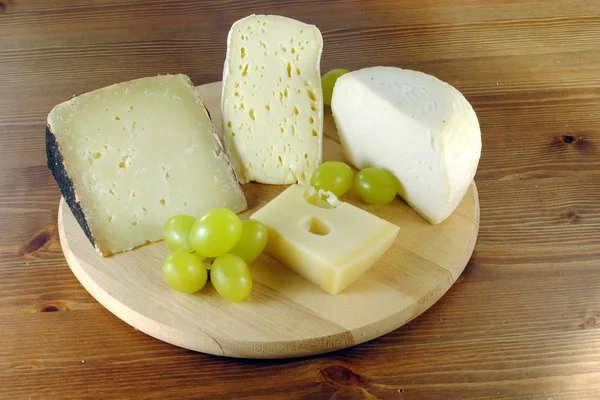 stock image Italian cheese with grapes on wooden cutting board