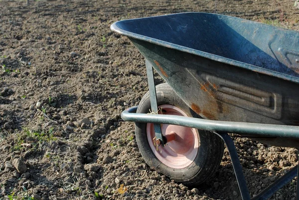 Old wheel barrow over soil in the garden — Stock Photo, Image