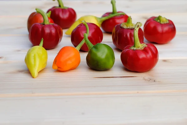 Hot chili papriky různých barev na dřevěné prkénko — Stock fotografie