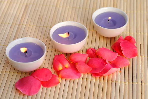 Três velas roxas com pétalas de rosa em bambu — Fotografia de Stock