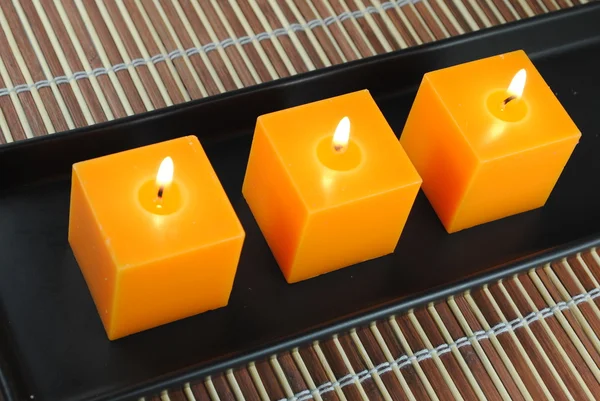 Trois bougies orange en plat noir sur bambou — Photo