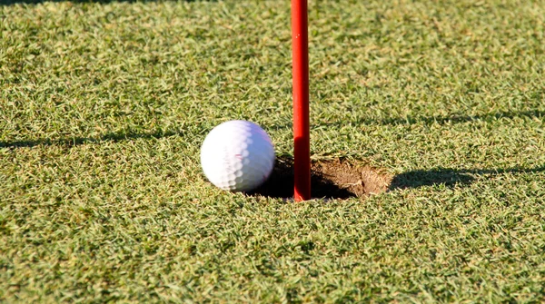 Мяч для гольфа возле лунки — стоковое фото