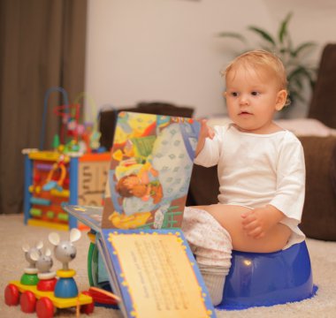 Cute toddler on potty with a book clipart