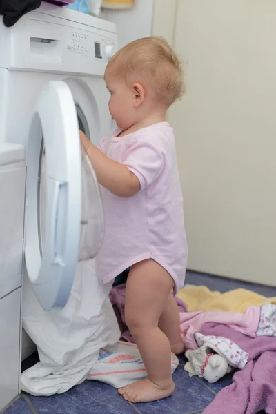 Маленькая девочка у стиральной машины — стоковое фото