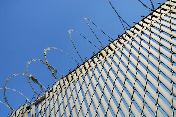 Fence with barbed wire against blue sky — Stock Photo, Image