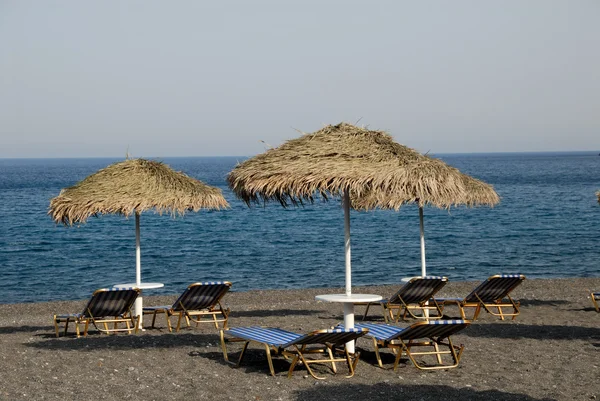 Ligstoelen op het strand van kamari in santorini, Griekenland — Stockfoto