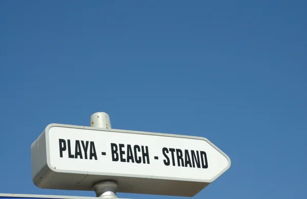 Firma por la playa en tres idiomas, español, inglés y alemán —  Fotos de Stock
