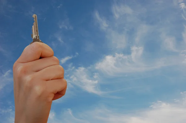Hand with key against sky — Stock Photo, Image
