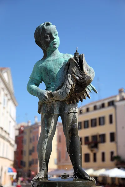 Мальчик со статуей рыбы в Ровине, Хорватия — стоковое фото