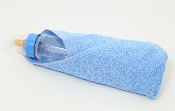 Closeup of a feeding bottle in blue towel — Stock Photo, Image
