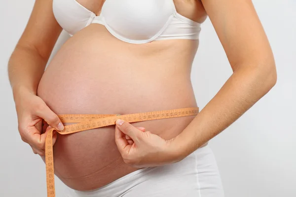 Pregnant woman measures her belly — Stock Photo, Image