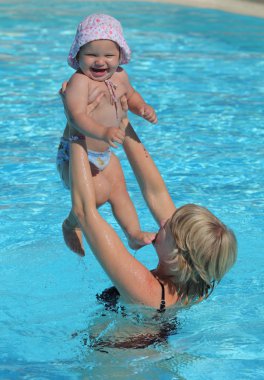 Mother with her toddler daughter in a swimming pool clipart