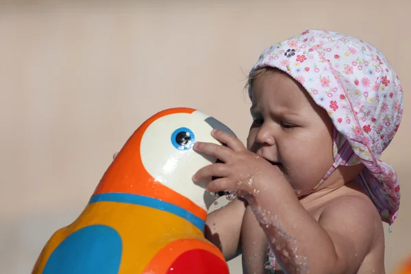 Söta barn flicka som leker med en leksak papegoja vid poolen — Stockfoto