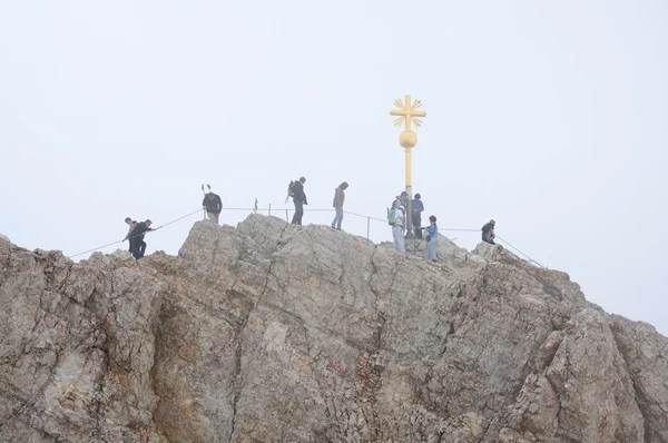 Turisté na kříž na vrcholu hory zugspitze, Alpy Německo. — Stock fotografie