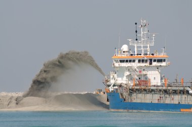 Special dredge ship pipe pushing sand to create new land in Dubai, United A clipart