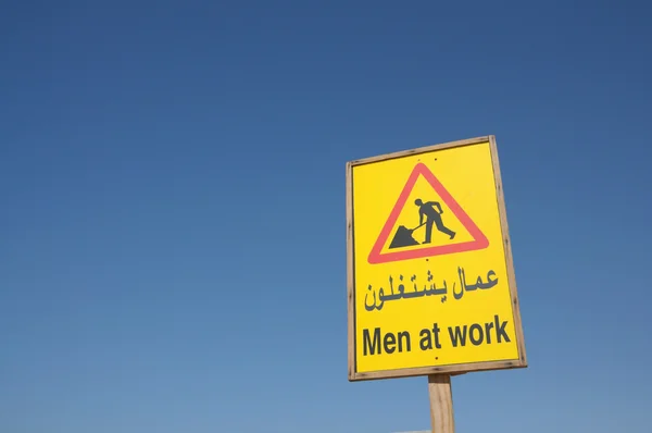 Men At Work sign against blue sky — Stock Photo, Image