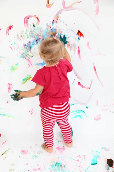 Petite fille tout-petit peinture avec des couleurs sur mur blanc — Photo