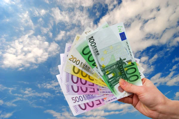 Hand med pengar mot en blå himmel — Stockfoto