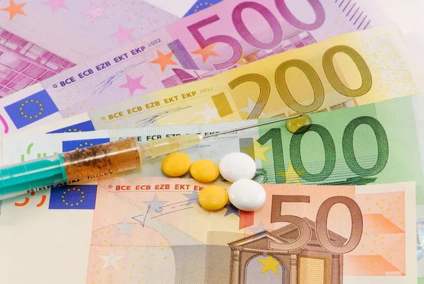 Jeringa y pastillas en el fondo del dinero — Foto de Stock