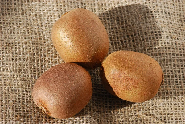 Three kiwis fruits on burlap — Stock Photo, Image