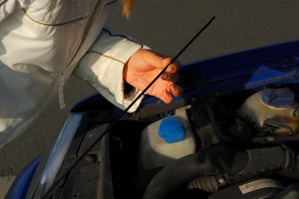 Uma mulher verificando o óleo do motor em seu carro — Fotografia de Stock