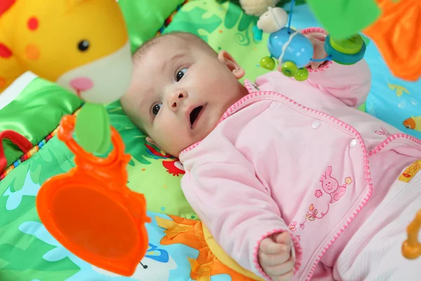 Little baby playing on a colorful jungle blanket — Stock Photo, Image