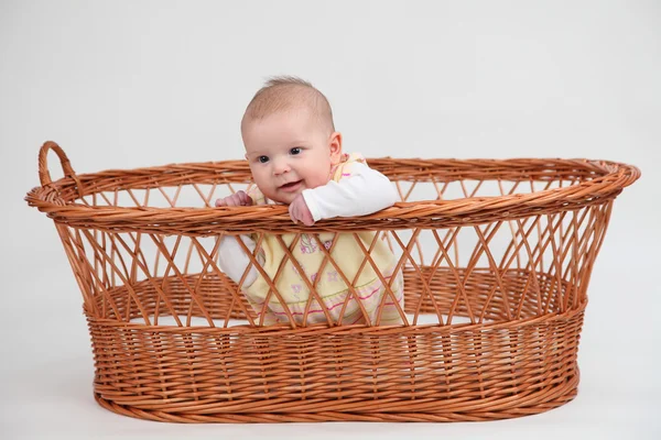 Pequena menina sentada em uma cesta — Fotografia de Stock