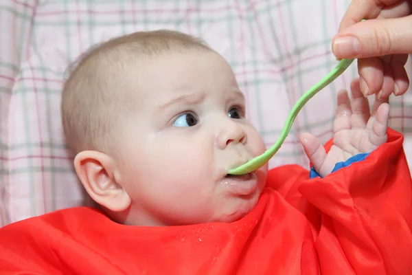Ilk kez bir kaşıkla. yulaf lapası yiyen bebek — Stok fotoğraf