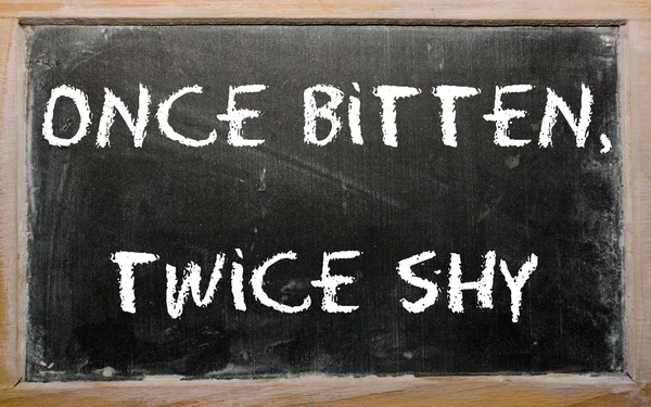 Proverb "Once bitten, twice shy" written on a blackboard — Stock Photo, Image