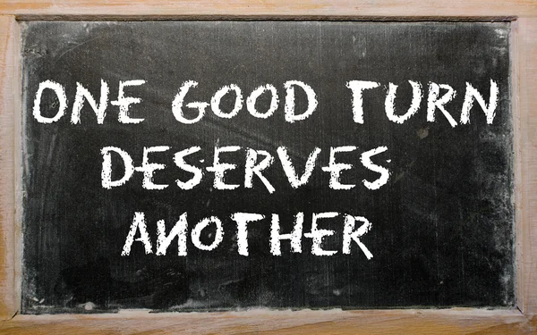 Spreekwoord "one good turn verdient een ander" geschreven op een schoolbord — Stockfoto
