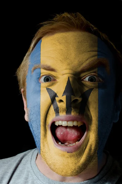 Face of crazy angry man painted in colors of Barbados flag — Stockfoto