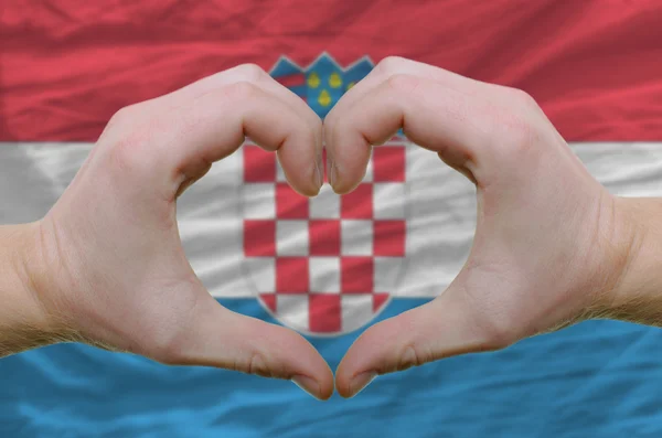 Cuore e amore gesto mostrato dalle mani sopra la bandiera della Croazia indietro — Foto Stock
