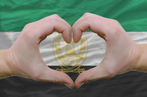 Srdce a lásku gestem ukázal rukou nad vlajka Afghánistánu — Stock fotografie