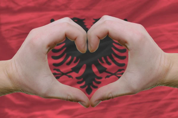 El corazón y el gesto de amor mostrados por las manos sobre la bandera de Albania espalda — Foto de Stock