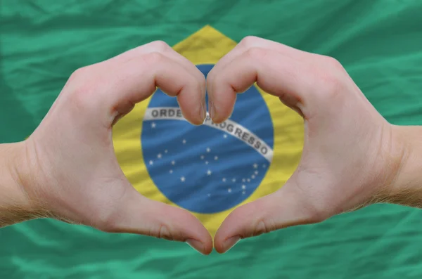 Srdce a lásku gestem ukázal rukou nad vlajkou Brazílie backg — Stock fotografie