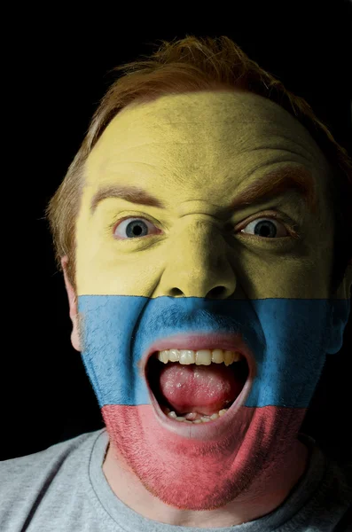 Gesicht des verrückten wütenden Mannes in den Farben der kolumbianischen Flagge gemalt — Stockfoto