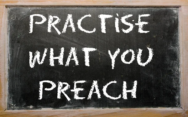 Sprichwort "Übe, was du predigst" steht auf einer Tafel — Stockfoto