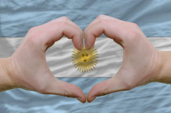 Srdce a lásku gestem ukázal rukou nad vlajkou Argentiny ba — Stock fotografie