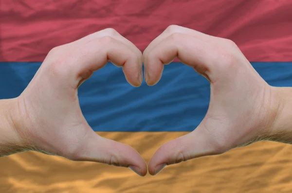 El corazón y el gesto de amor mostrados por las manos sobre la bandera de Armenia — Foto de Stock