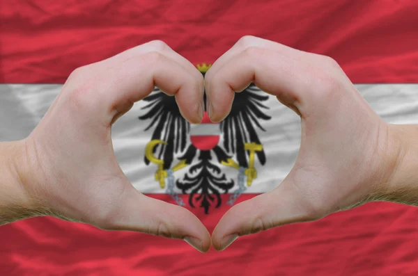 Srdce a lásku gestem ukázal rukou nad vlajkou Rakouska zpět — Stock fotografie