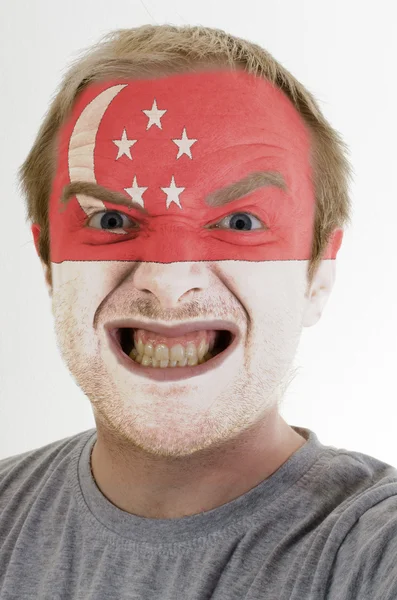 Лицо безумного злобного человека, раскрашенного в цвета сингапорского флага — стоковое фото