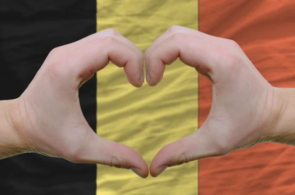 Srdce a lásku gestem ukázal rukou nad vlajkou Belgie zpět — Stock fotografie