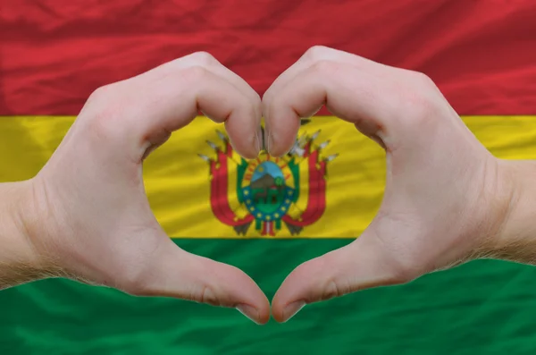 Srdce a lásku gestem ukázal rukou nad vlajky Bolívie zpět — Stock fotografie