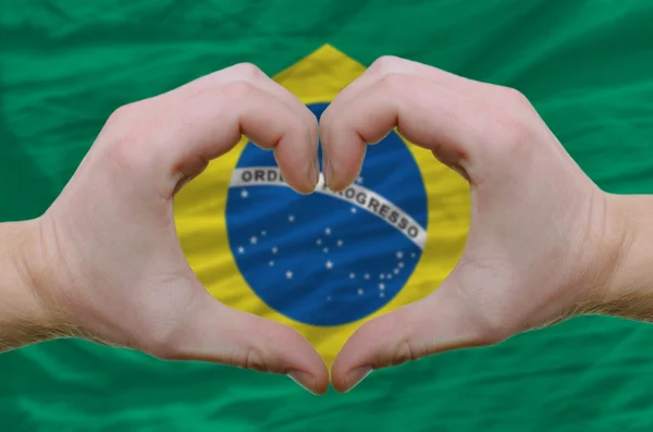 El corazón y el gesto de amor mostrado por las manos sobre la bandera de Brasil backg — Foto de Stock