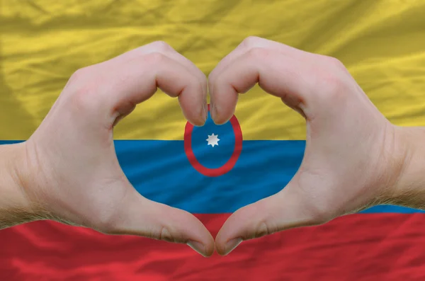 Srdce a lásku gestem ukázal rukou nad vlajka Kolumbie bac — Stock fotografie