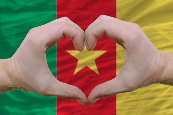Srdce a lásku gestem ukázal rukou nad vlajka Kamerunu bac — Stock fotografie