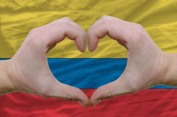 Srdce a lásku gestem ukázal rukou nad vlajka Kolumbie bac — Stock fotografie